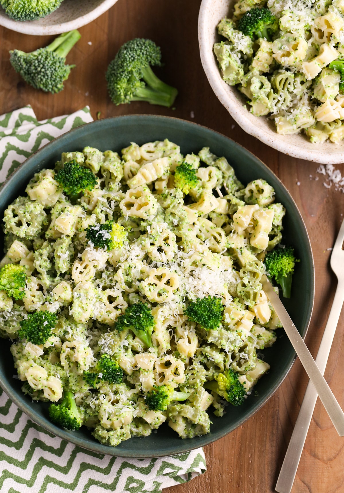 Close up of two bowls of creamy broccoli pasta with fresh broccoli florets surrounding bowls.