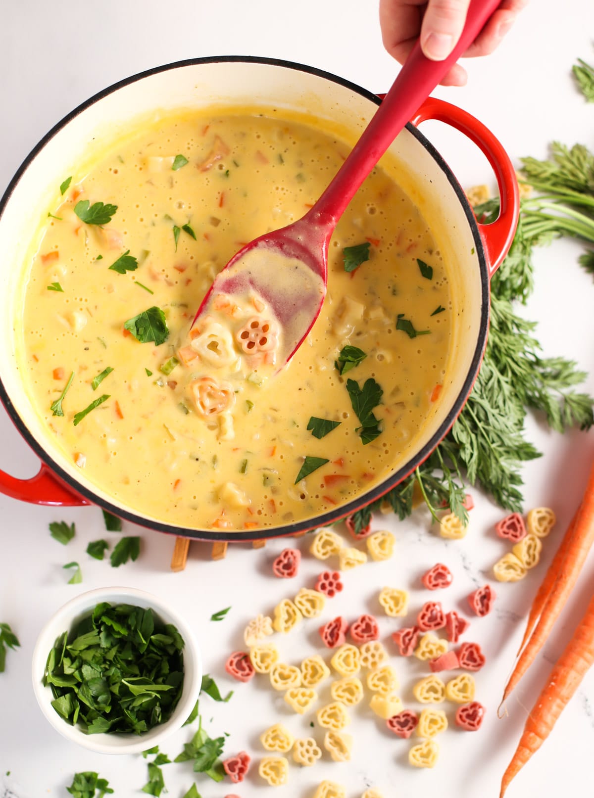 Mac and Cheese Soup in Large Pot with red spoon and ingredients on table