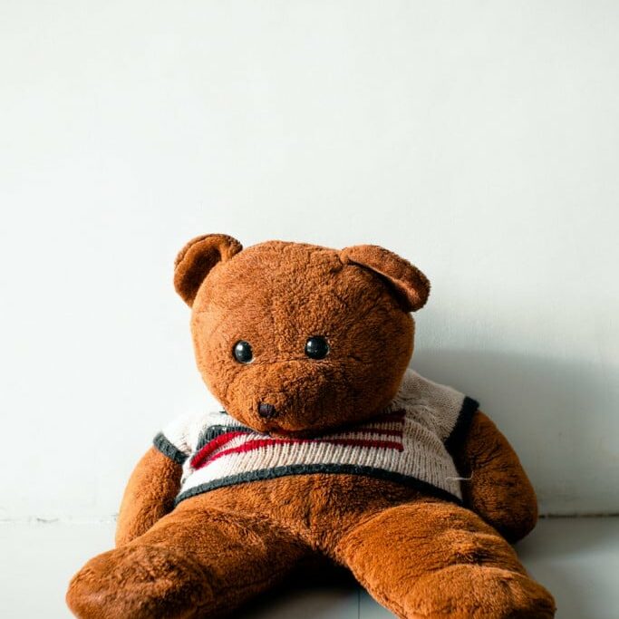 teddy bear lying against wall