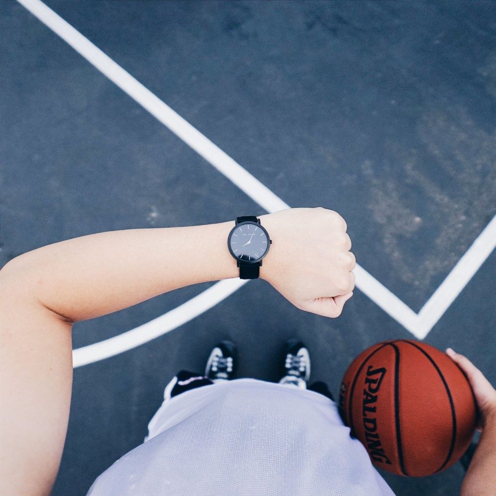 person holing a basketball and checking their watch