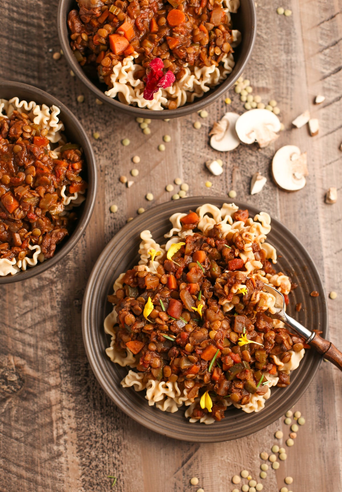 Three bowls of lentil bolognese with mushrooms and lentils in background